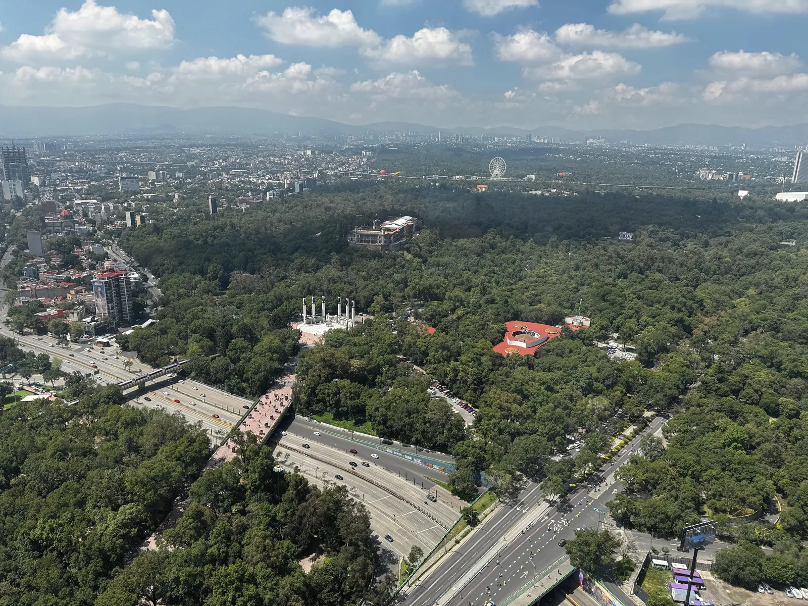A stunning aerial view of Chapultepec Park with cityscape and mountains in the background.