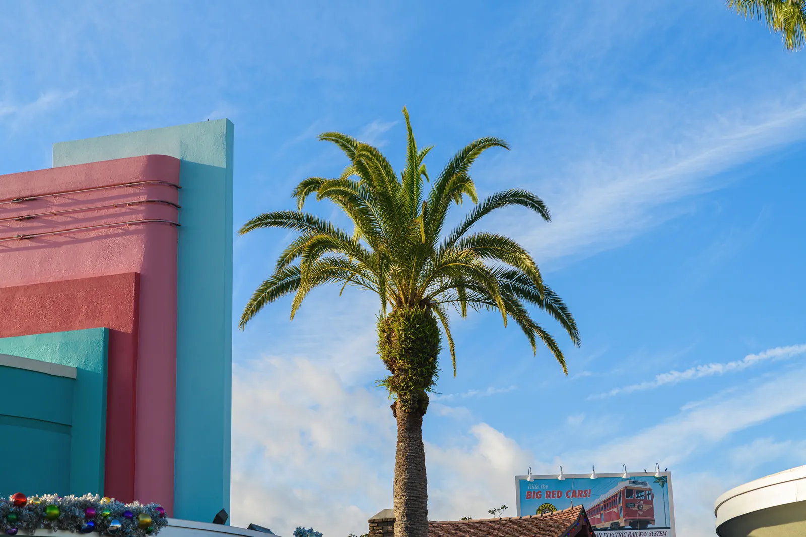 Palm tree with vivid retro architecture under a clear blue sky.