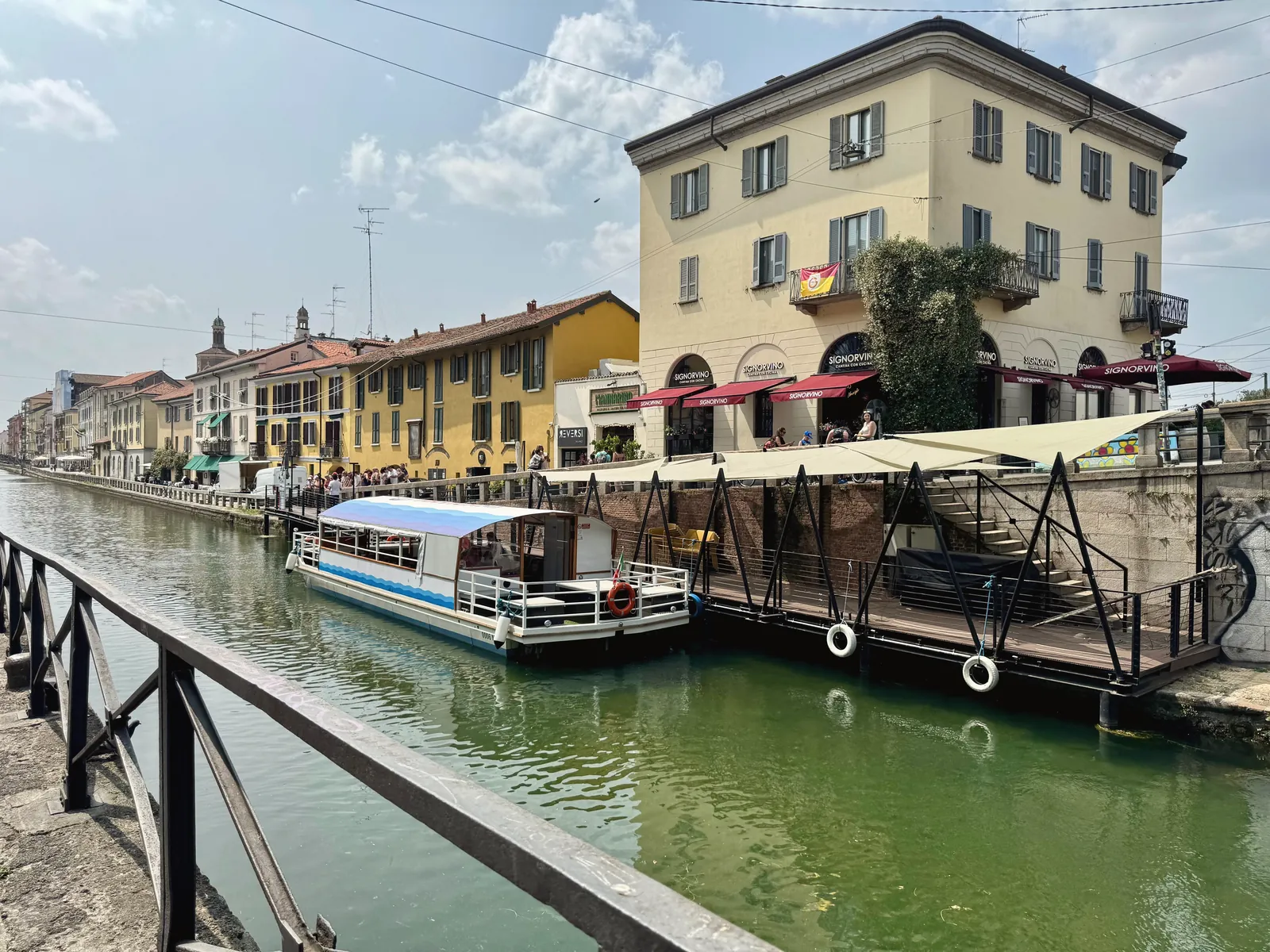 A picturesque view of the Navigli canal in Milan, Italy, featuring colorful buildings and a docked boat.
