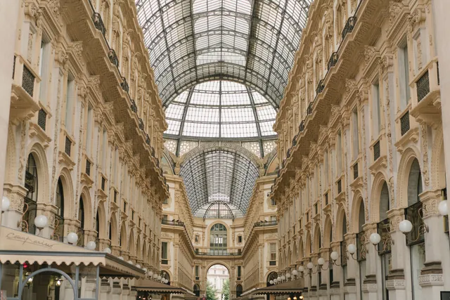 Low angle of aged stone shopping gallery with arching glass roof and ornamental walls