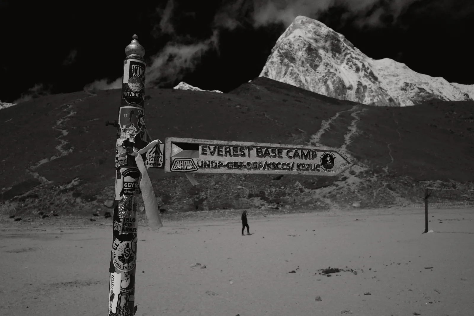 Directional sign leading to Everest Base Camp with mountains in monochrome setting.