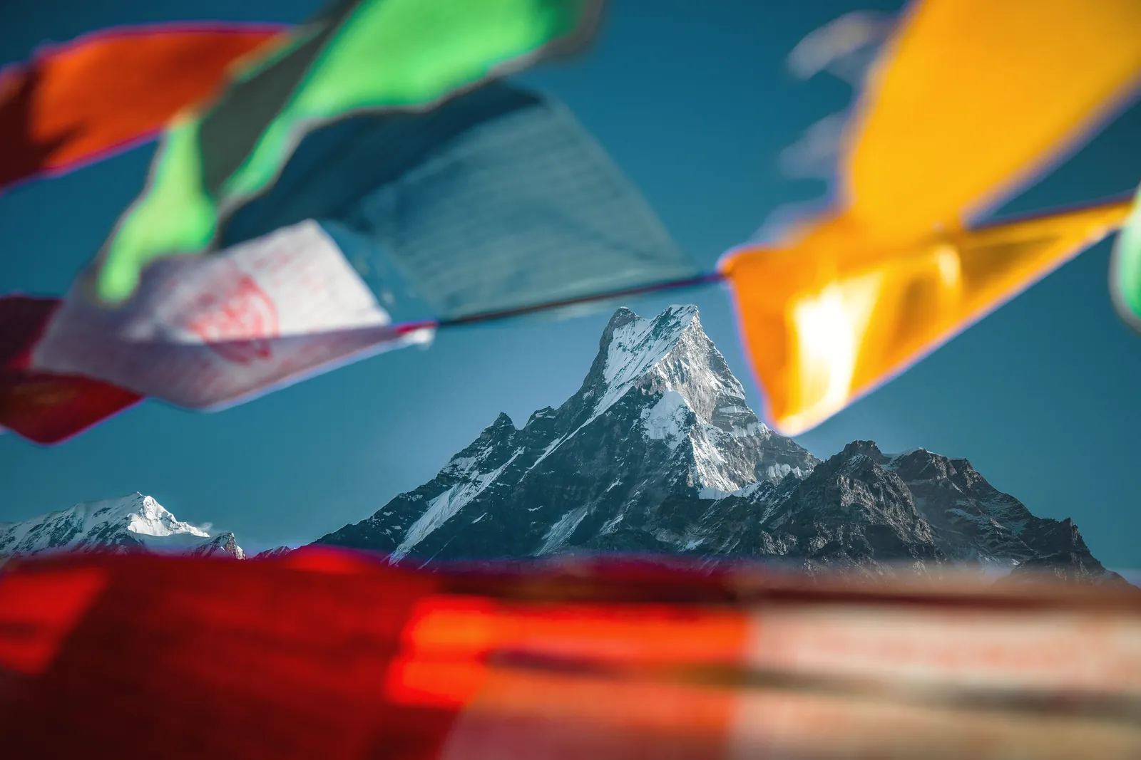 Majestic mountain peak surrounded by vibrant prayer flags in the Himalayas, Nepal.