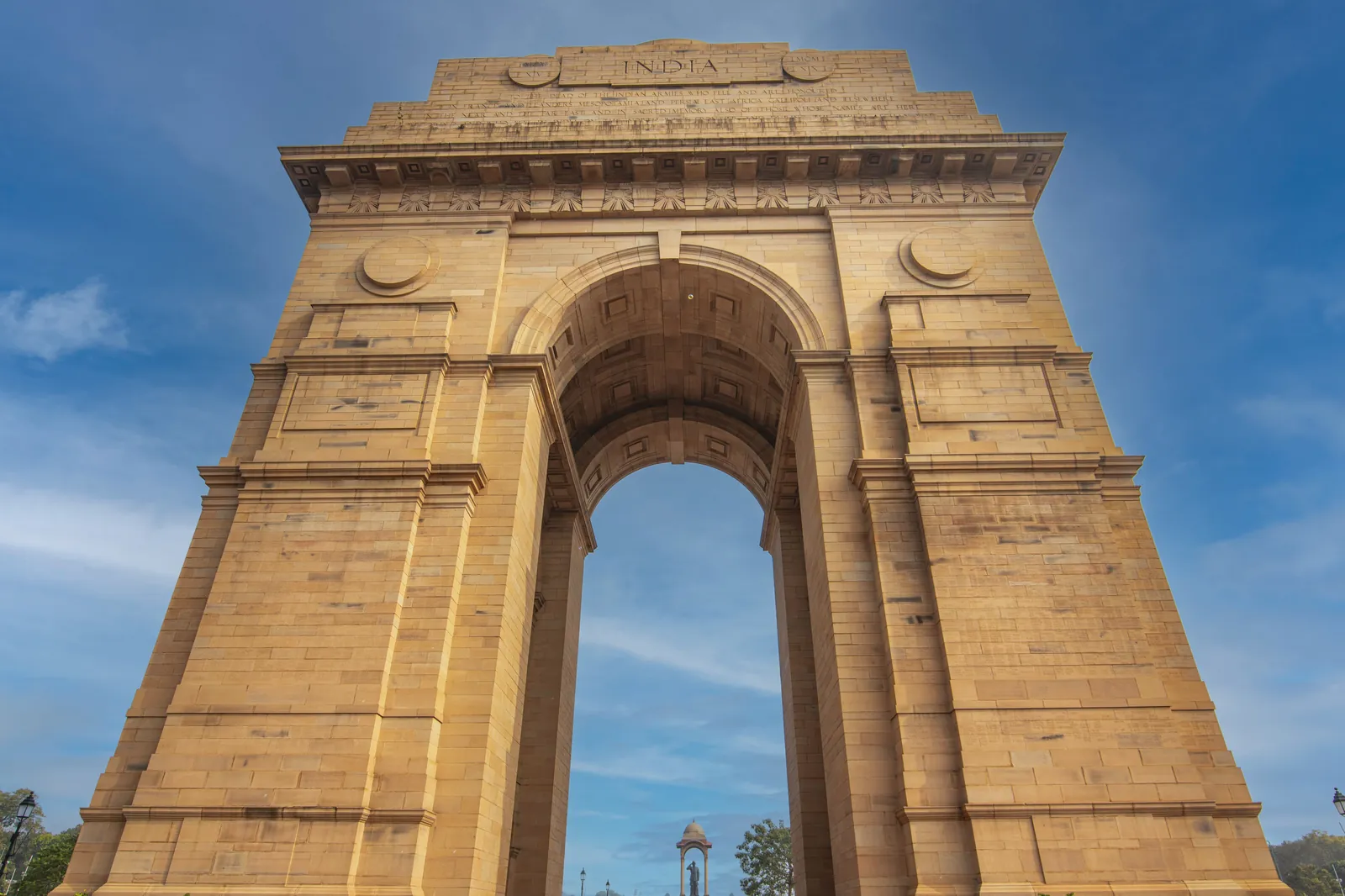 Stunning low-angle shot of the iconic India Gate monument in Delhi against a blue sky.