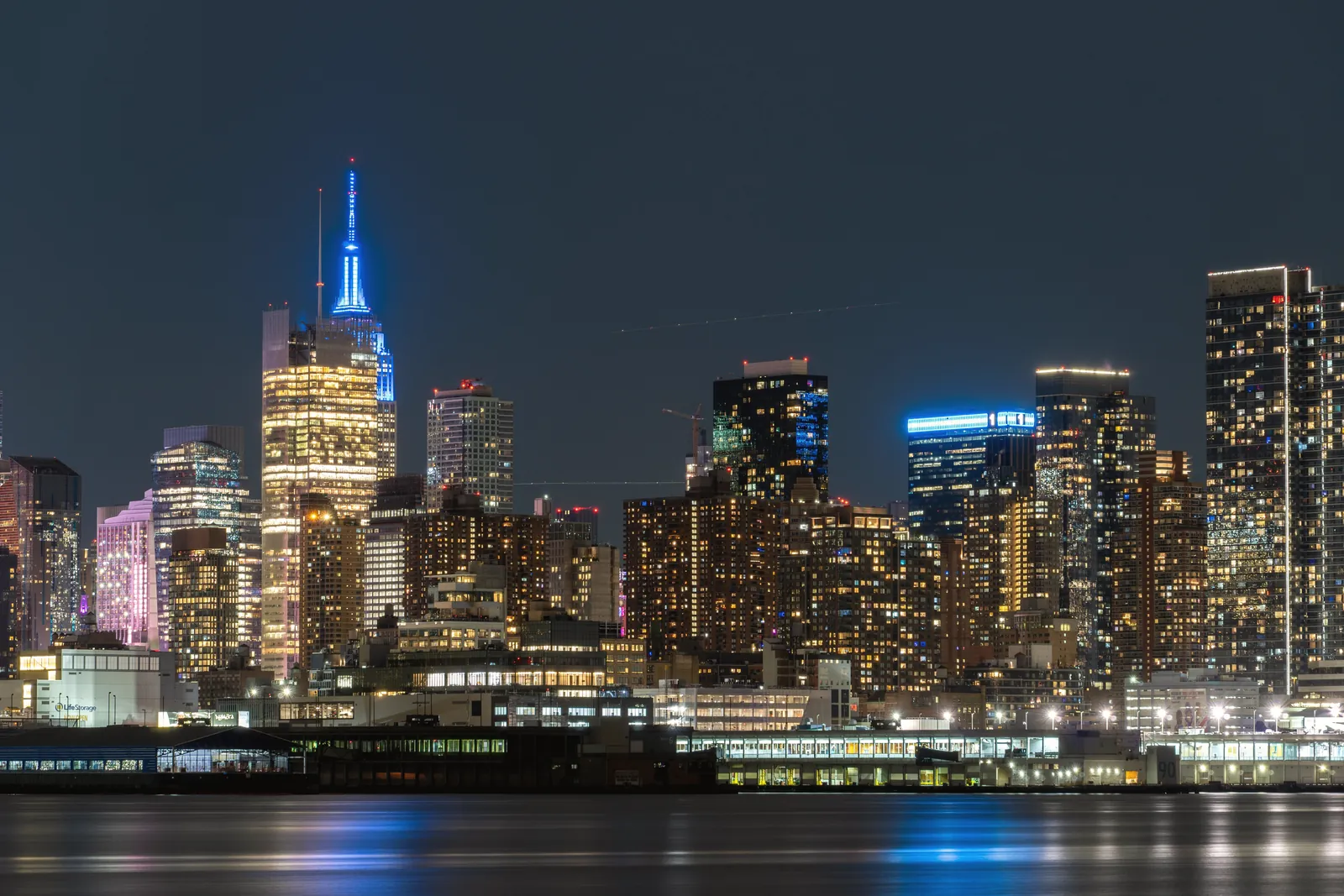 Stunning night view of New York City's skyline reflecting on the water, showcasing vibrant urban architecture.