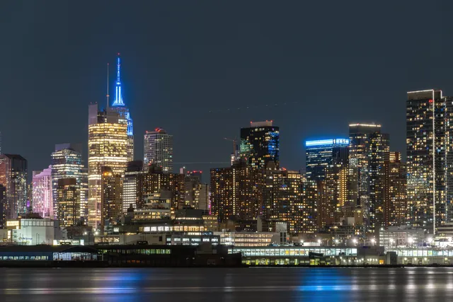 Stunning night view of New York City's skyline reflecting on the water, showcasing vibrant urban architecture.