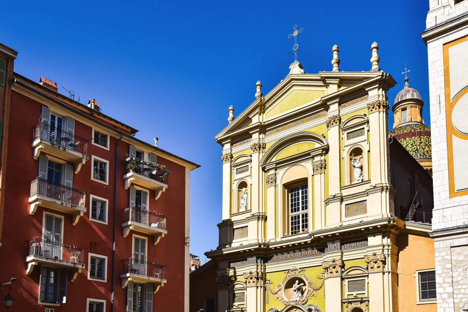 Vibrant facade of historical buildings in Nice, France under clear blue sky.
