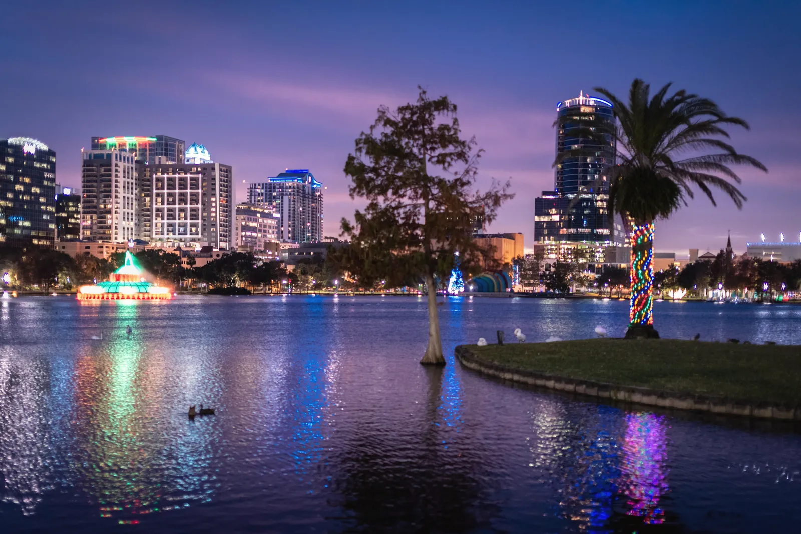 Vibrant Orlando city skyline reflected in Lake Eola at twilight, capturing the festive atmosphere.