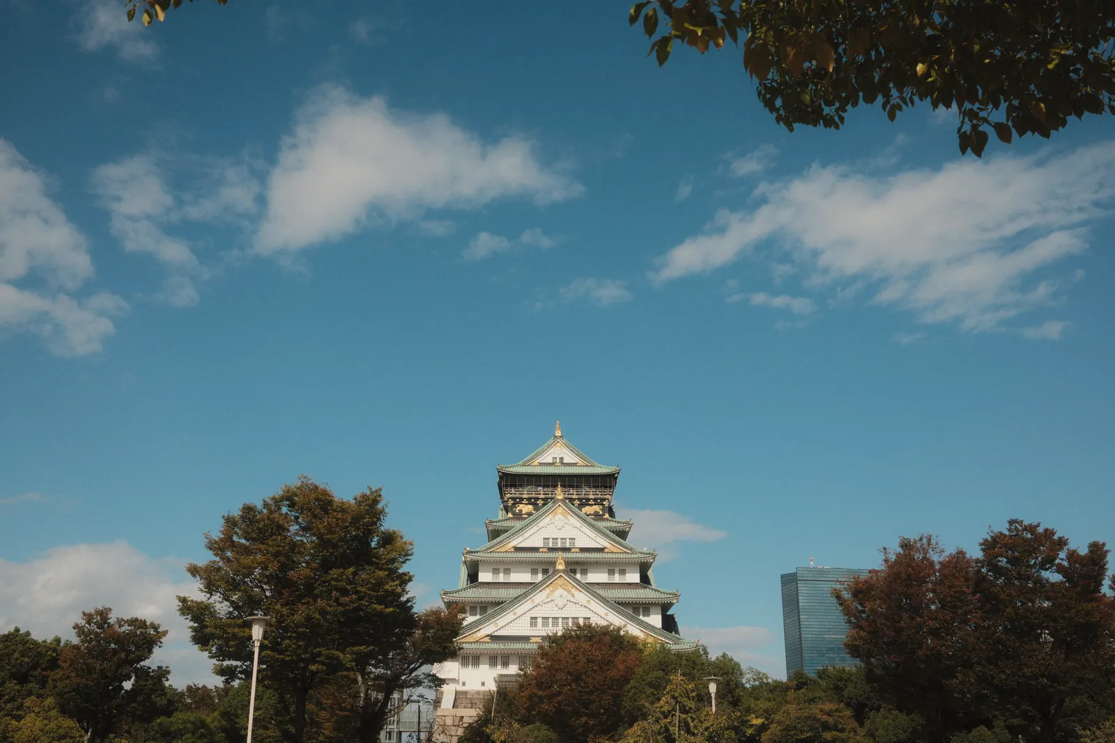 Capture of the iconic Osaka Castle surrounded by trees and a clear blue sky in Osaka, Japan.