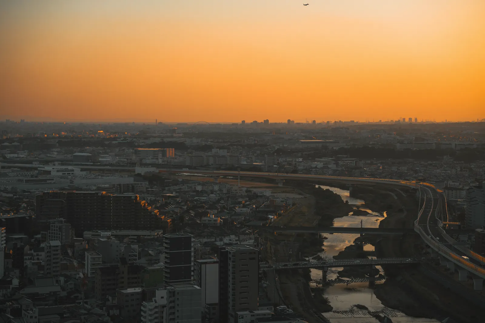 Capture of Ikeda City skyline at sunset with river and vibrant sky.