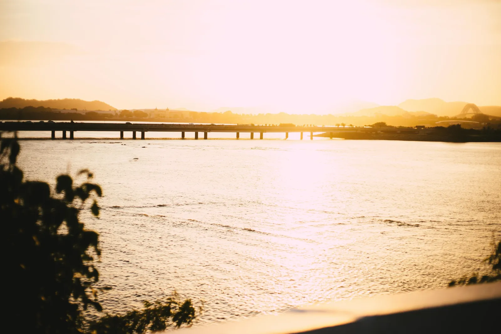 Scenic view of a bridge over a river in Panama at sunset, capturing tranquil sunlight reflections.
