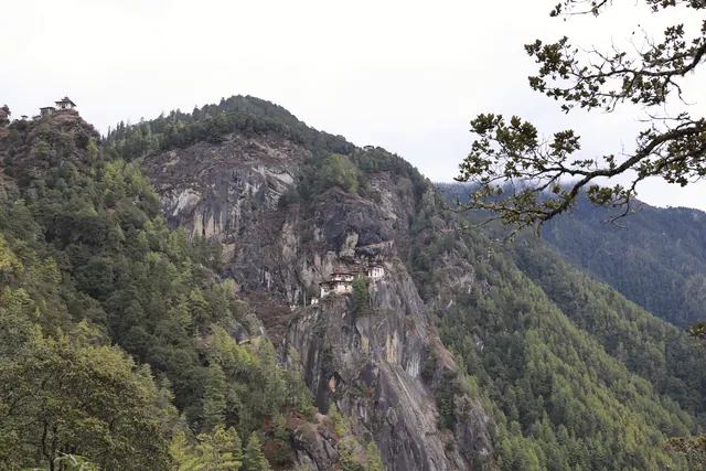 Breathtaking view of Tiger's Nest Monastery in Bhutan, perched on a cliff amidst forested mountains.