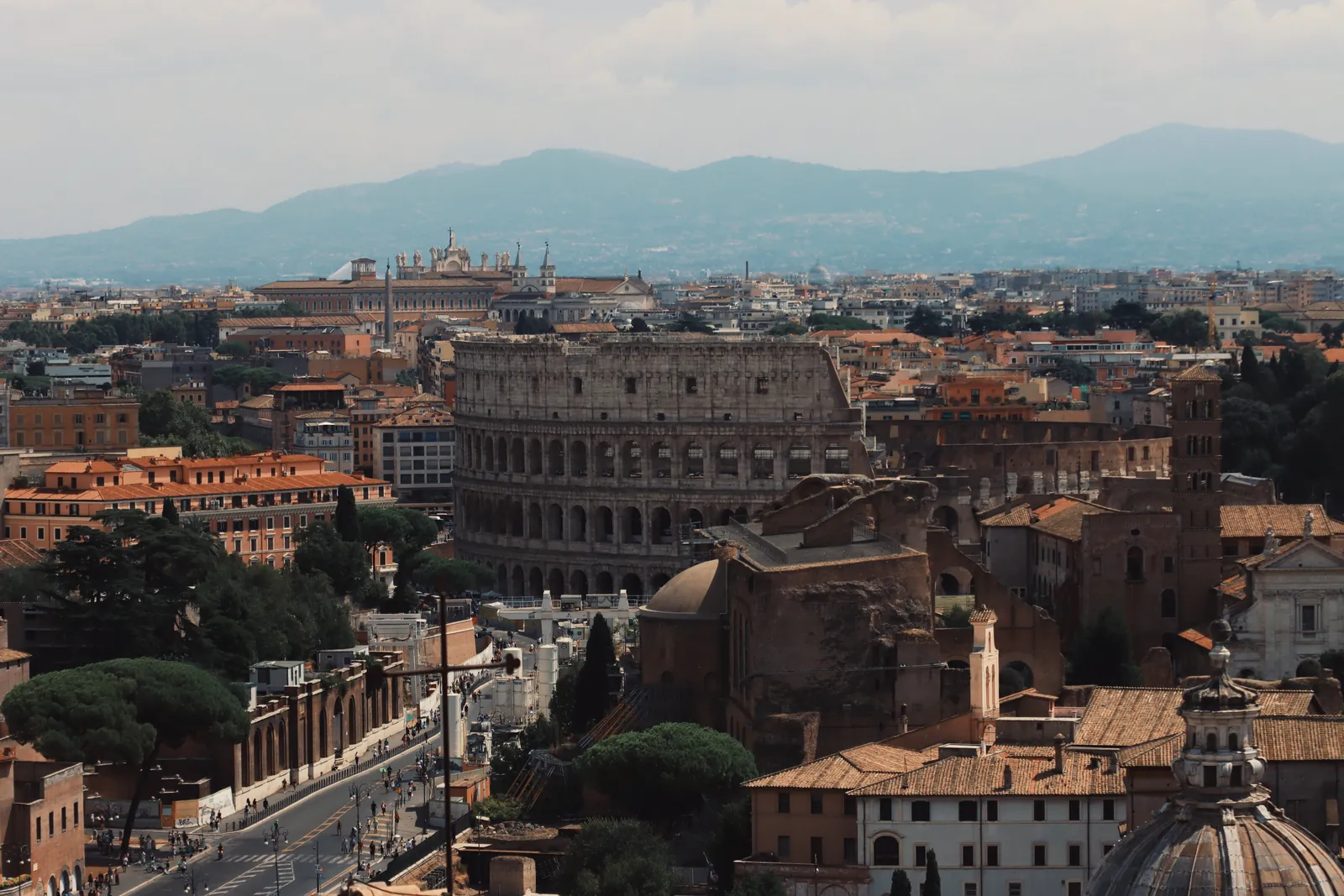 Drone shot of the iconic Colosseum and surrounding cityscape in Rome, Italy.