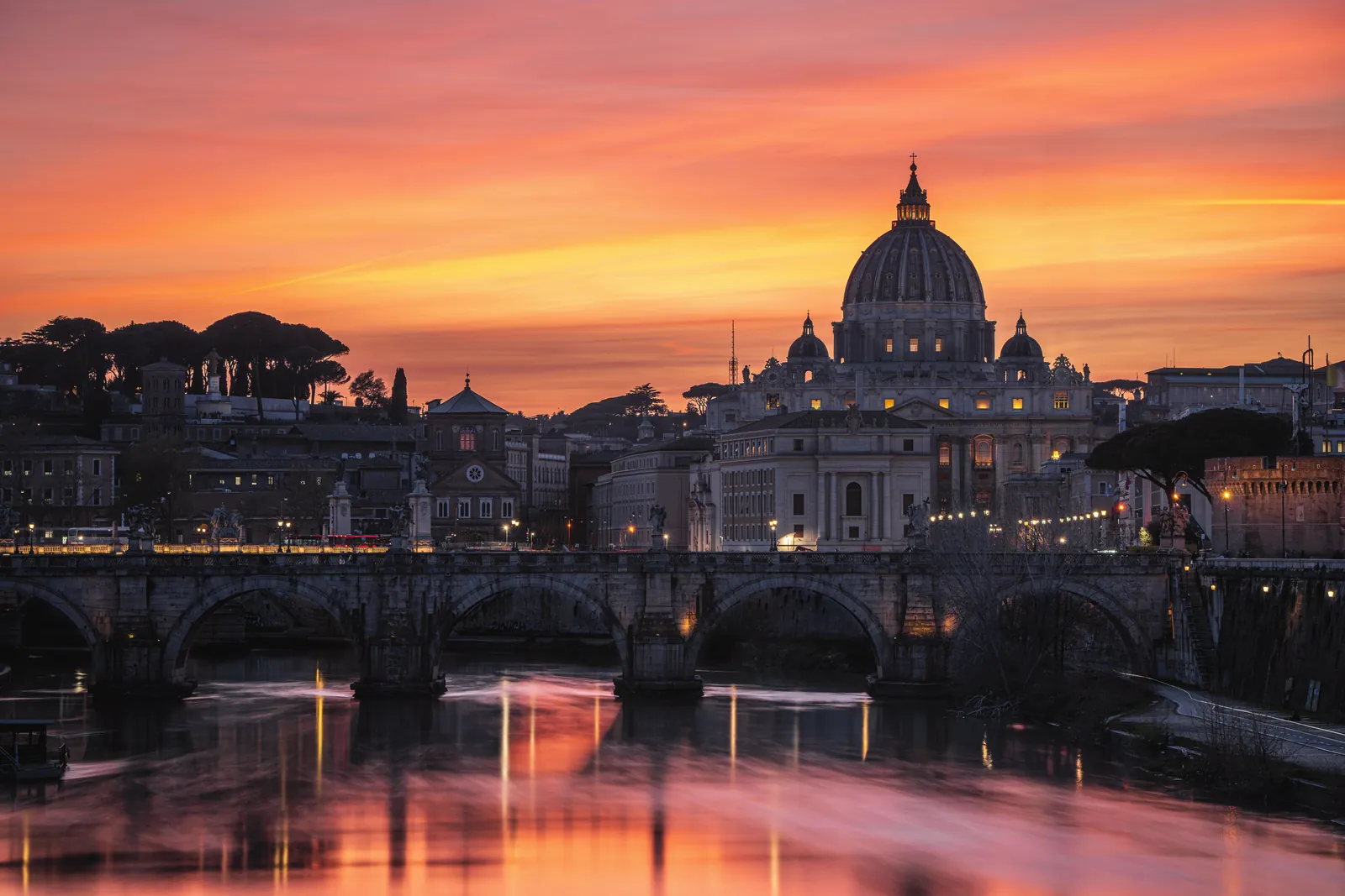 Breathtaking view of St. Peter's Basilica at sunset, reflecting over the River Tiber in Rome, Italy.