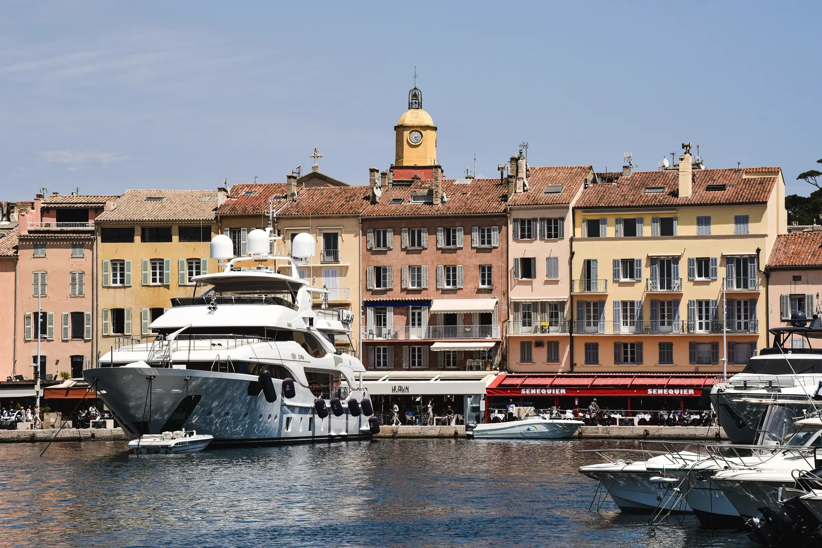 Scenic view of luxury yachts docked at Saint-Tropez harbor with charming French architecture.