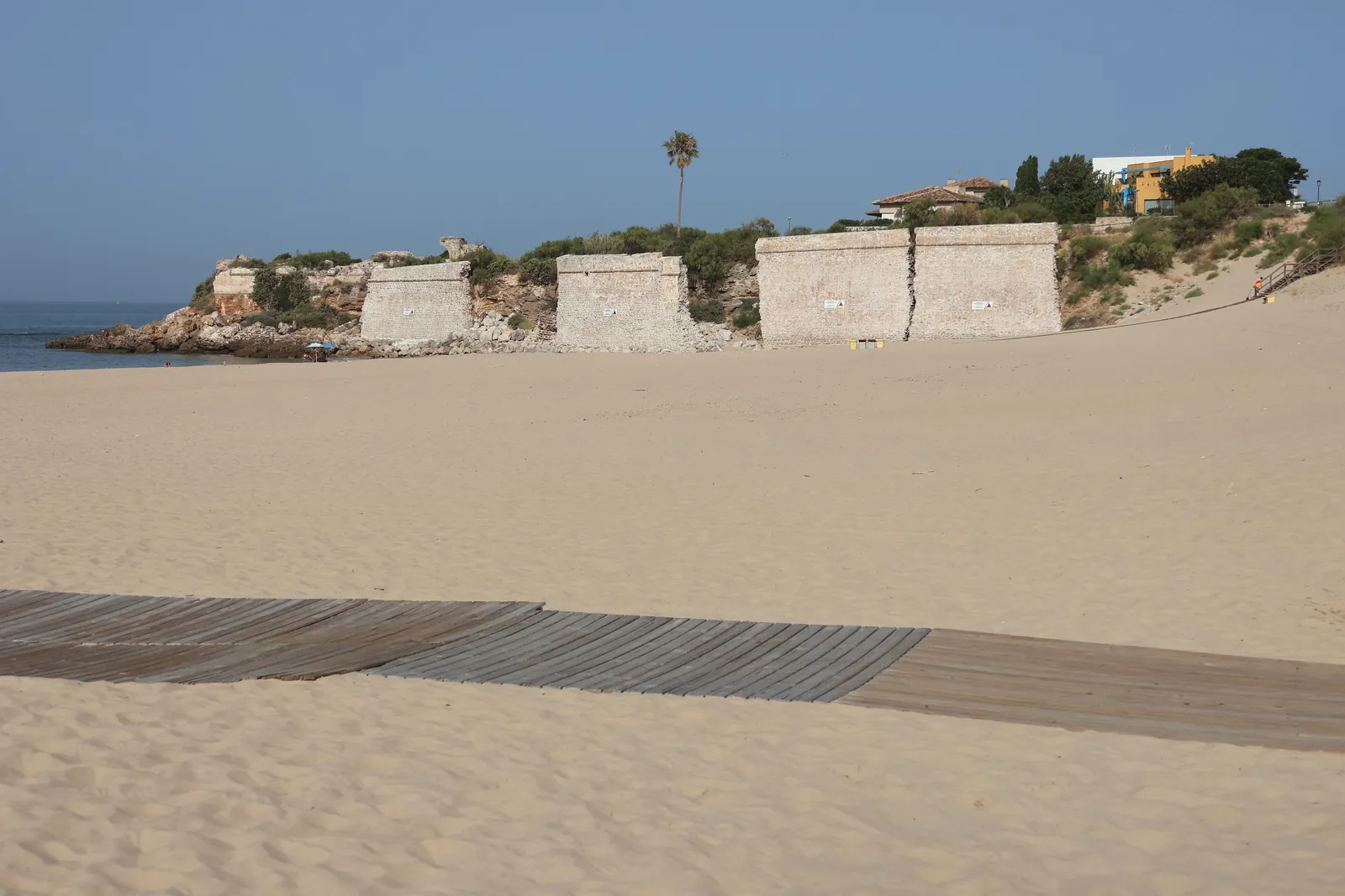 A serene beach scene at El Puerto de Santa María, featuring sandy shores and historic fortifications.