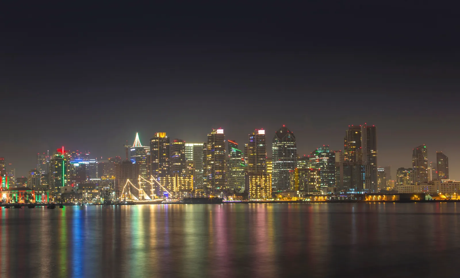A serene night view of San Diego's illuminated skyline reflecting on calm water.