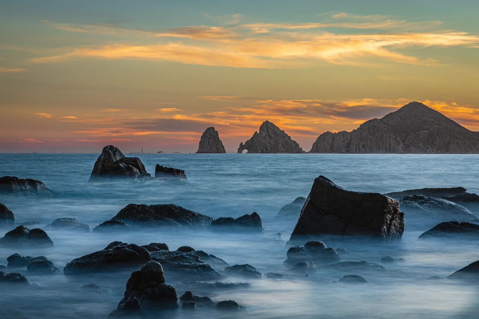 Stunning long exposure of rocky seascape at sunset in Cabo San Lucas, Mexico.