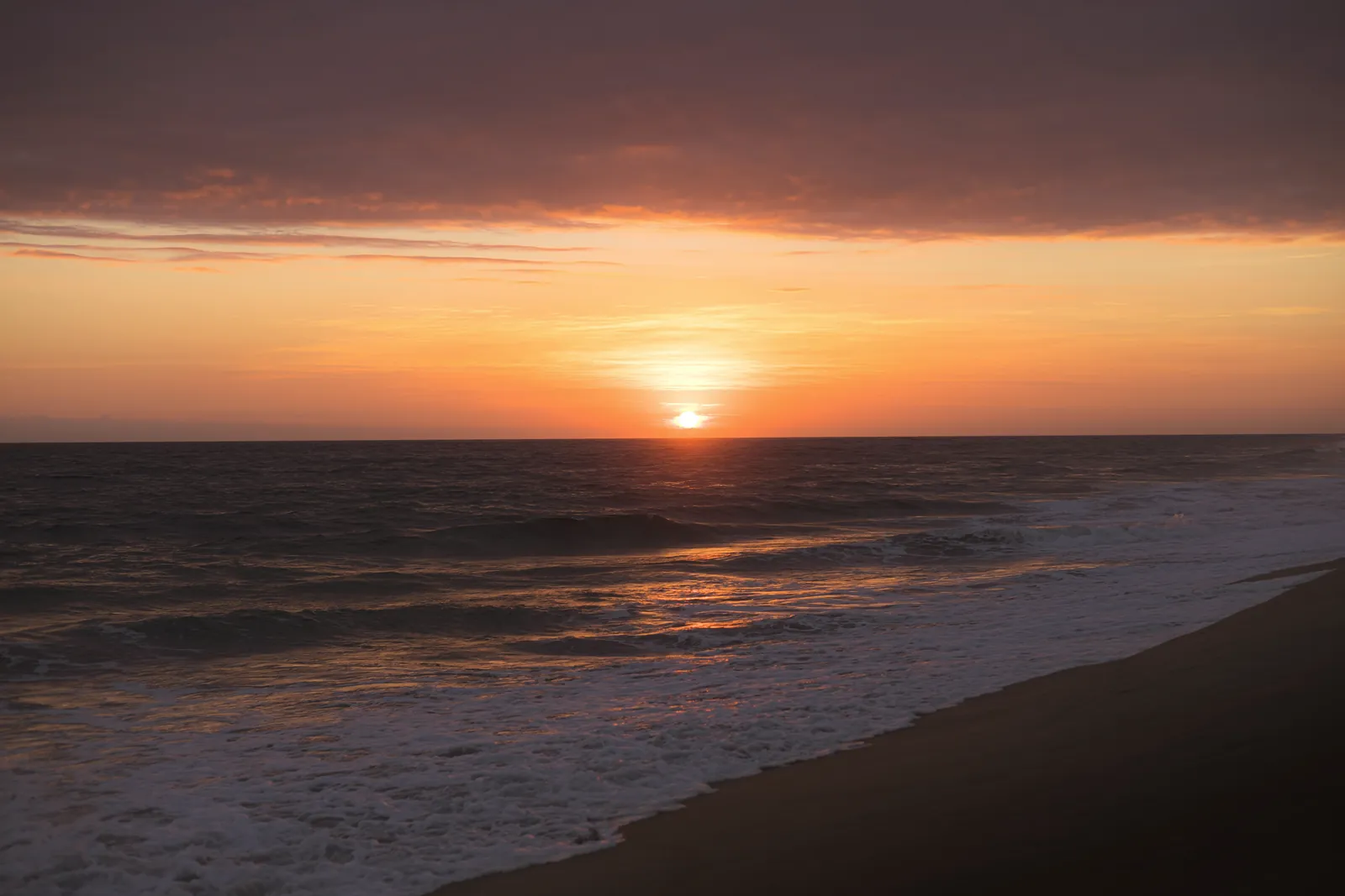 Serene view of a sunset over Puerto Escondido beach, capturing the vibrant ocean hues.