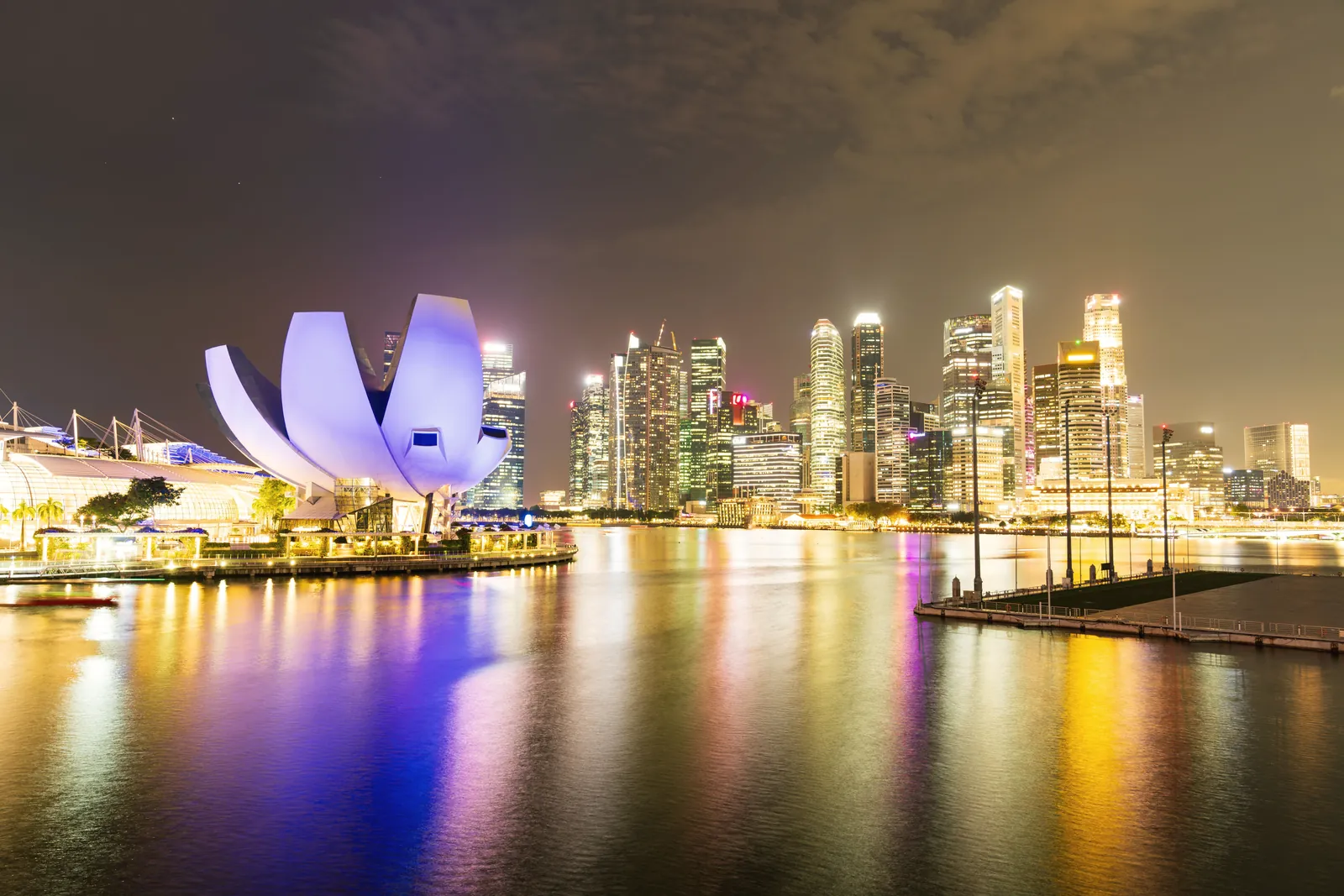 Night view of Singapore's illuminated skyline and Marina Bay Sands, reflecting vibrant city lights.