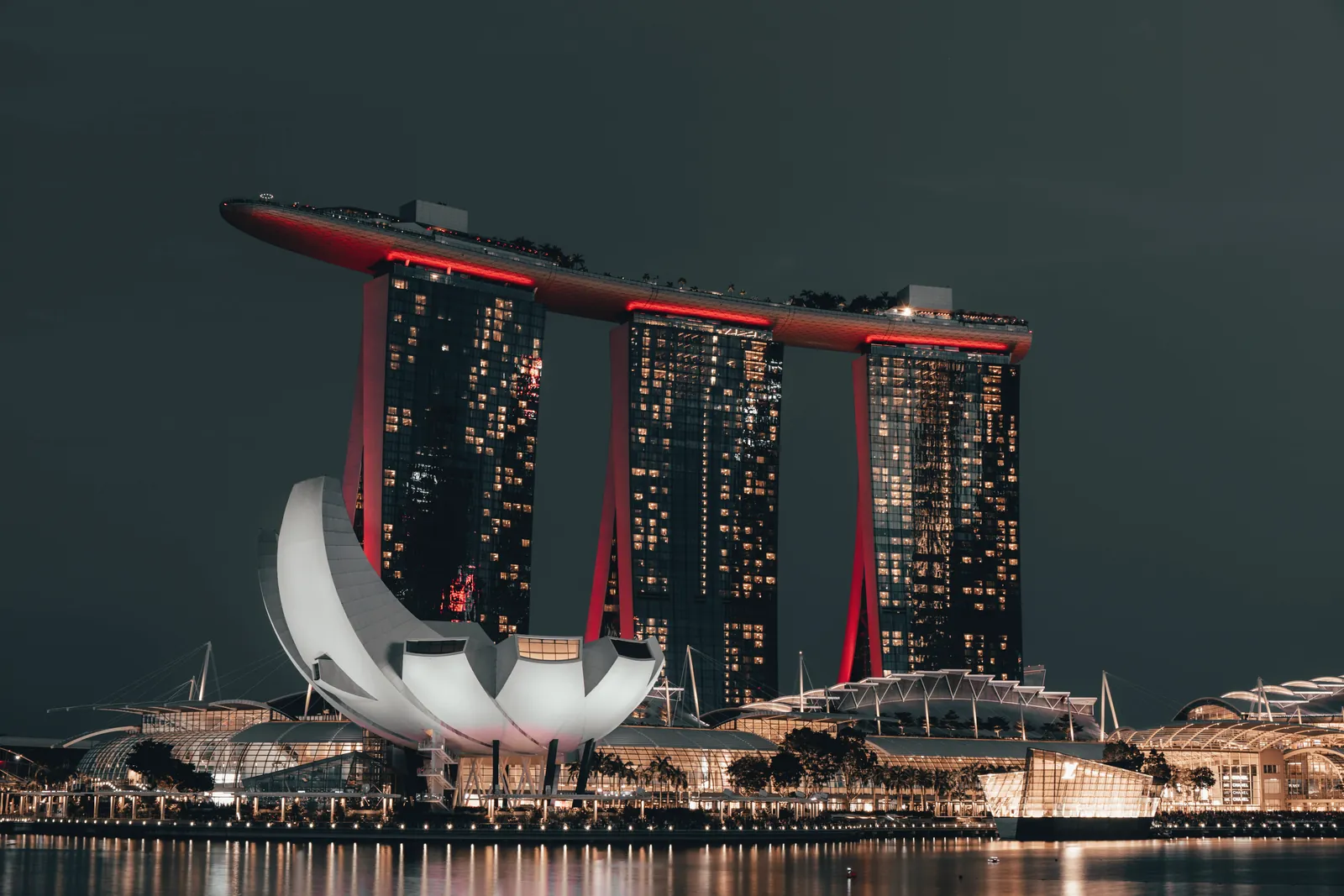 Dramatic night view of Marina Bay Sands, Singapore, with glowing cityscape and reflection.