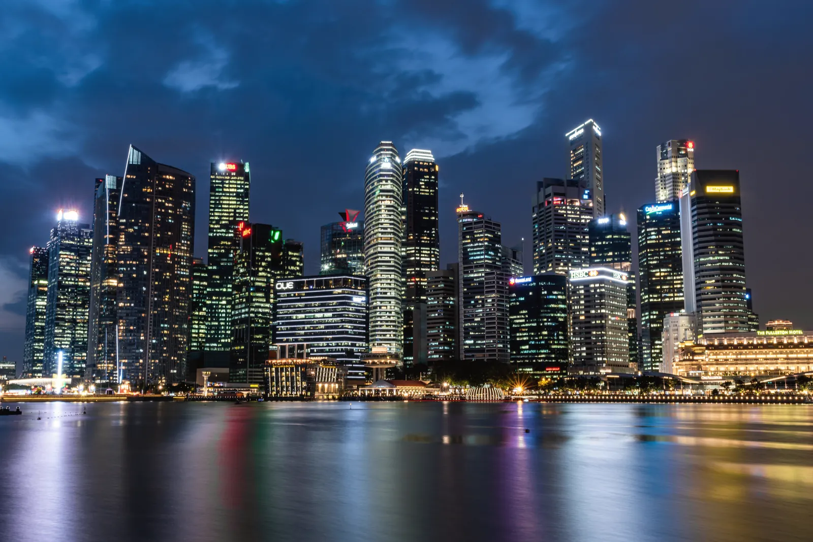 Illuminated Singapore skyline reflecting beautifully on waterfront at night.