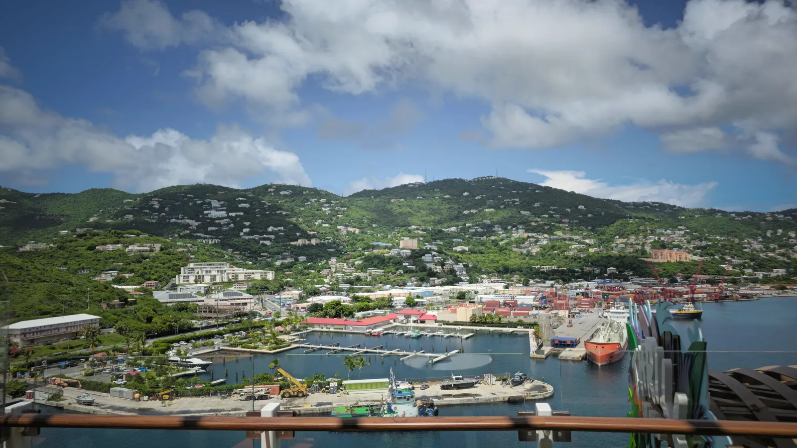 Aerial view of Charlotte Amalie Harbor in St. Thomas with vibrant buildings and lush green hills.