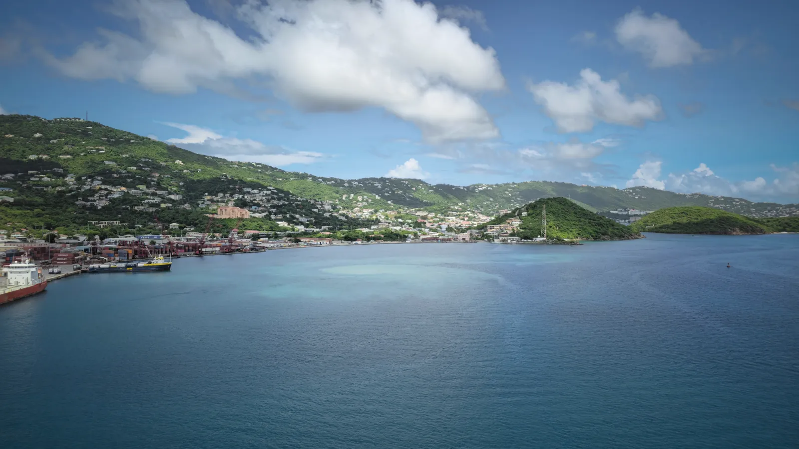Explore the vibrant and scenic harbor of St. Thomas with lush green hills and clear blue water, perfect for a tropical getaway.