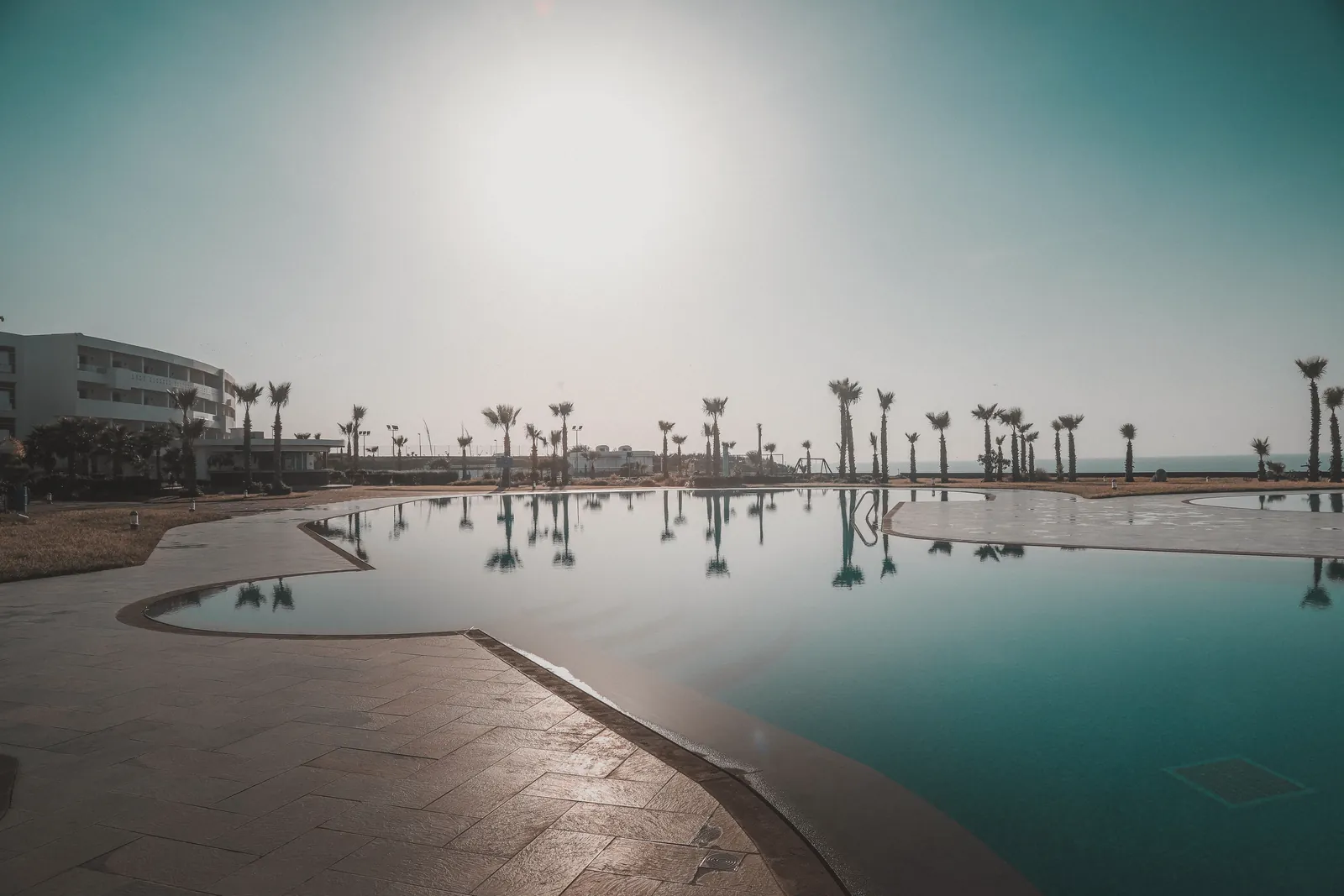 Idyllic scene of a resort pool with palm trees under a stunning Moroccan sunset