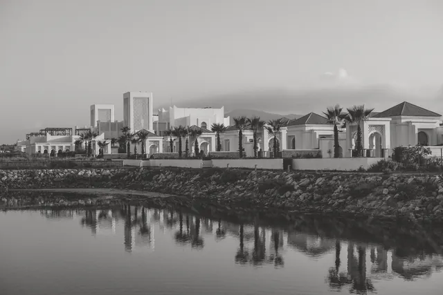 Black and white photo of modern Moroccan architecture by a calm waterfront in Fnideq, Morocco.