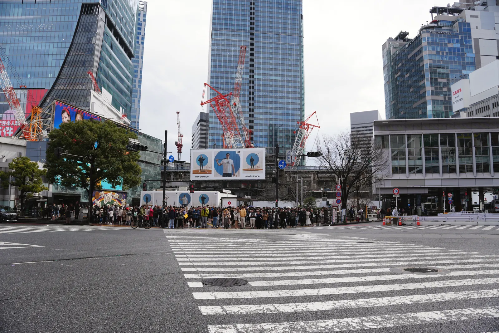 Crowd at a busy Tokyo intersection surrounded by modern skyscrapers and urban architecture.