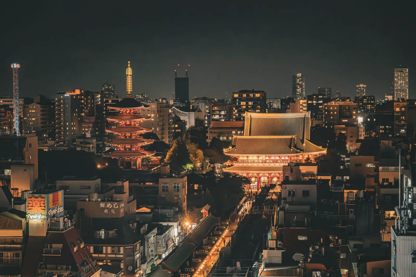 Stunning nighttime aerial view of Senso-ji Temple and Tokyo skyline in Taito City, Japan.