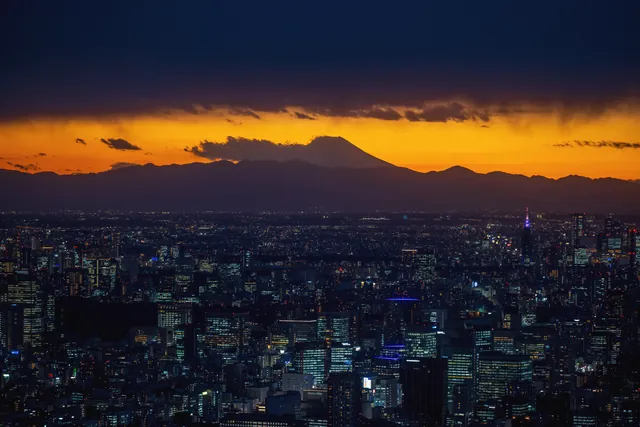 Breathtaking view of Tokyo skyline with Mount Fuji silhouetted against a vibrant sunset sky.
