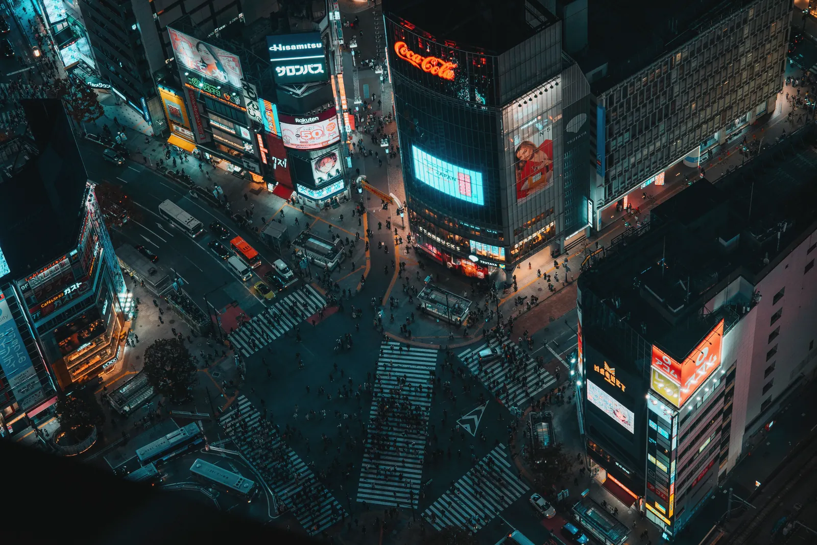 Vibrant aerial view of Shibuya Scramble Crossing in Tokyo at night, showcasing bustling city life and neon lights.