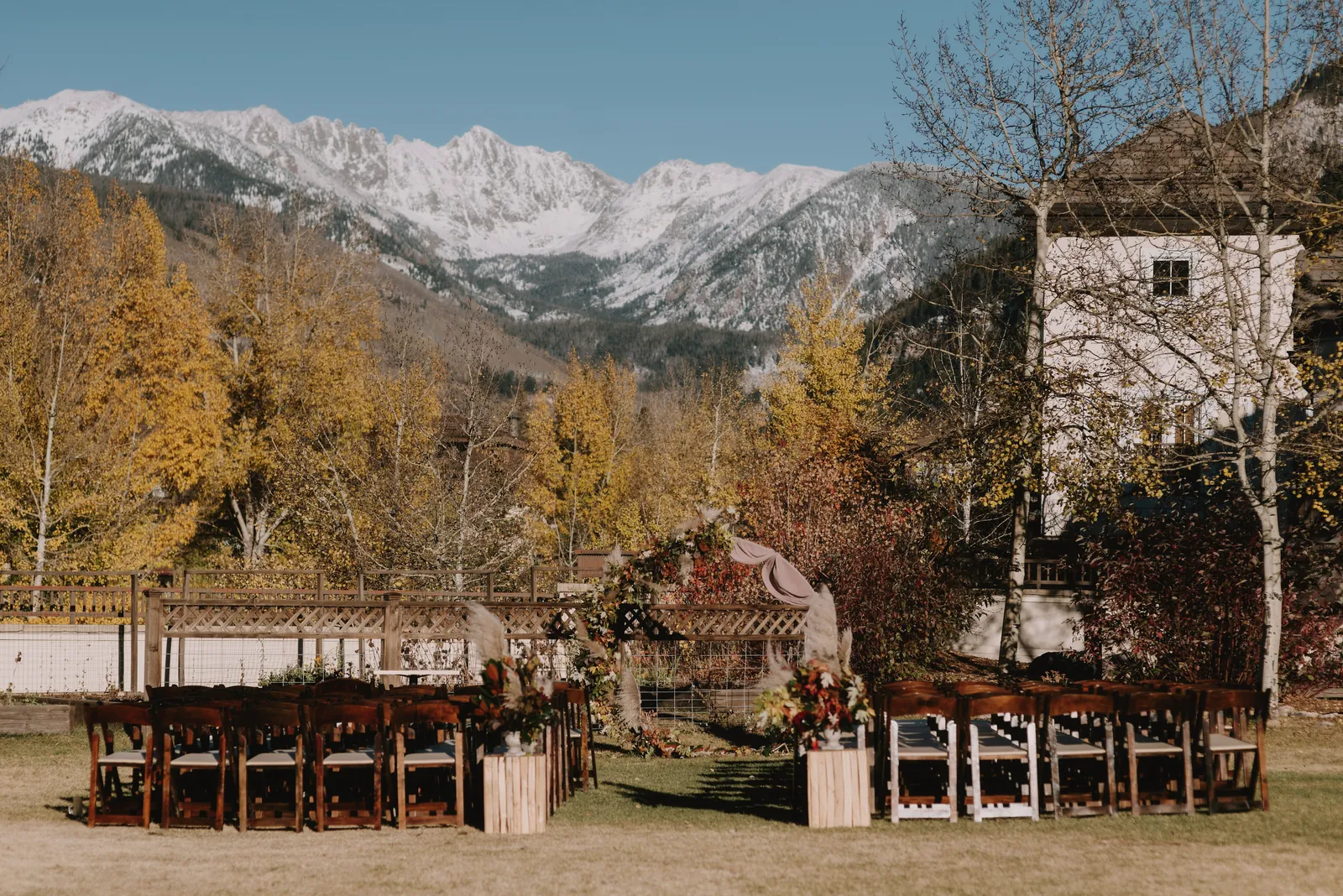 Outdoor wedding venue in Vail, Colorado, with a backdrop of autumn foliage and snowcapped mountains.