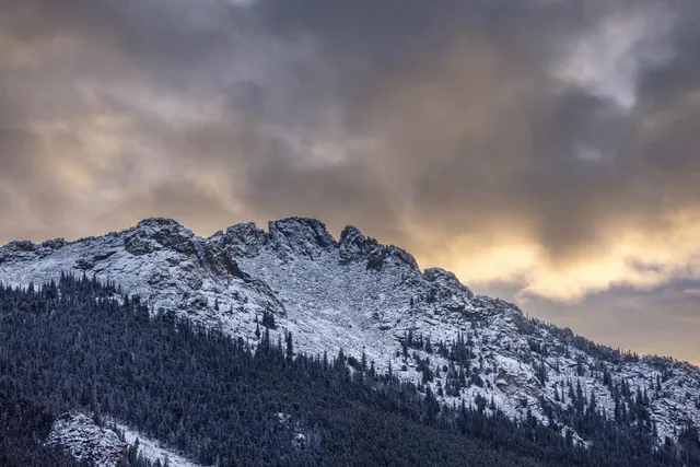 Stunning view of snow-dusted peaks of the Rocky Mountains in Estes Park during sunset.