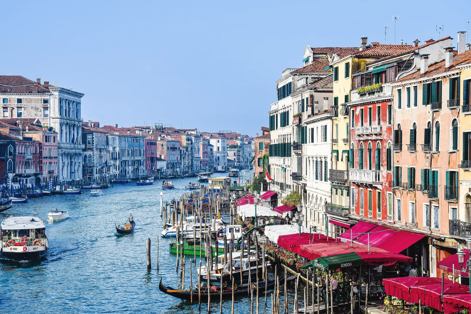 Scenic view of Venice's Grand Canal with colorful buildings and gondolas under a clear sky.