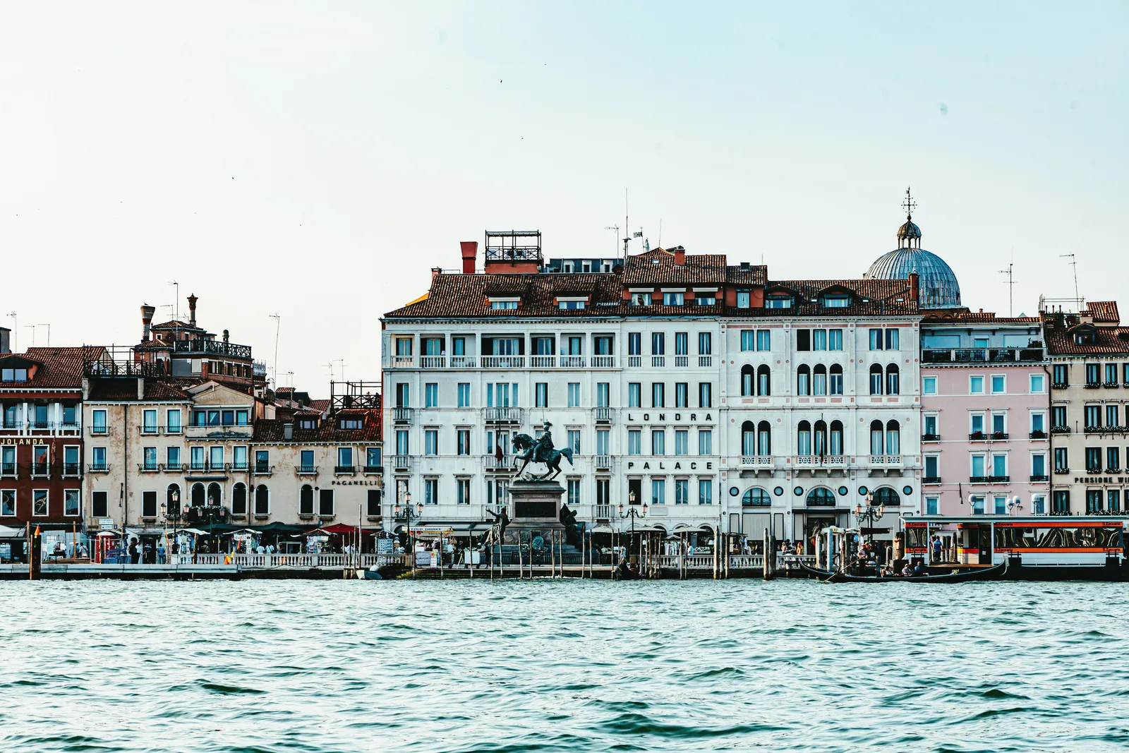 Historic buildings line the water in Venice, Italy, under a clear sky.