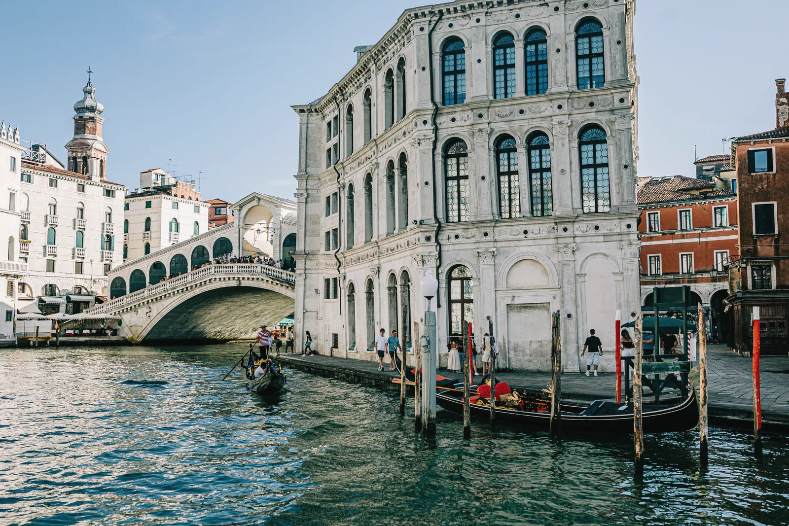 Scenic view of Rialto Bridge over the Grand Canal in Venice with gondolas and historic architecture.