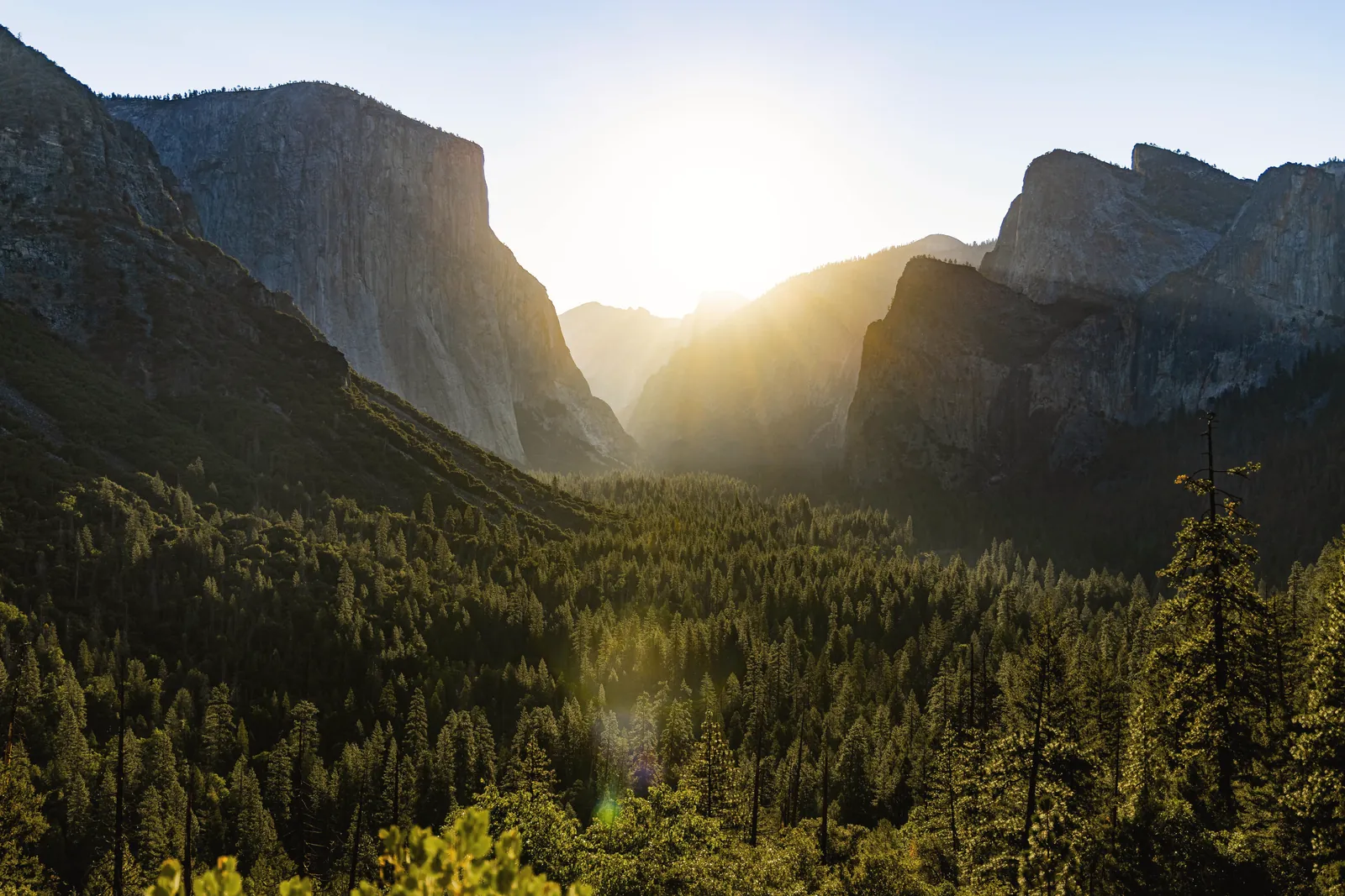 Breathtaking view of sunrise over Yosemite National Park, highlighting cliffs and forests.