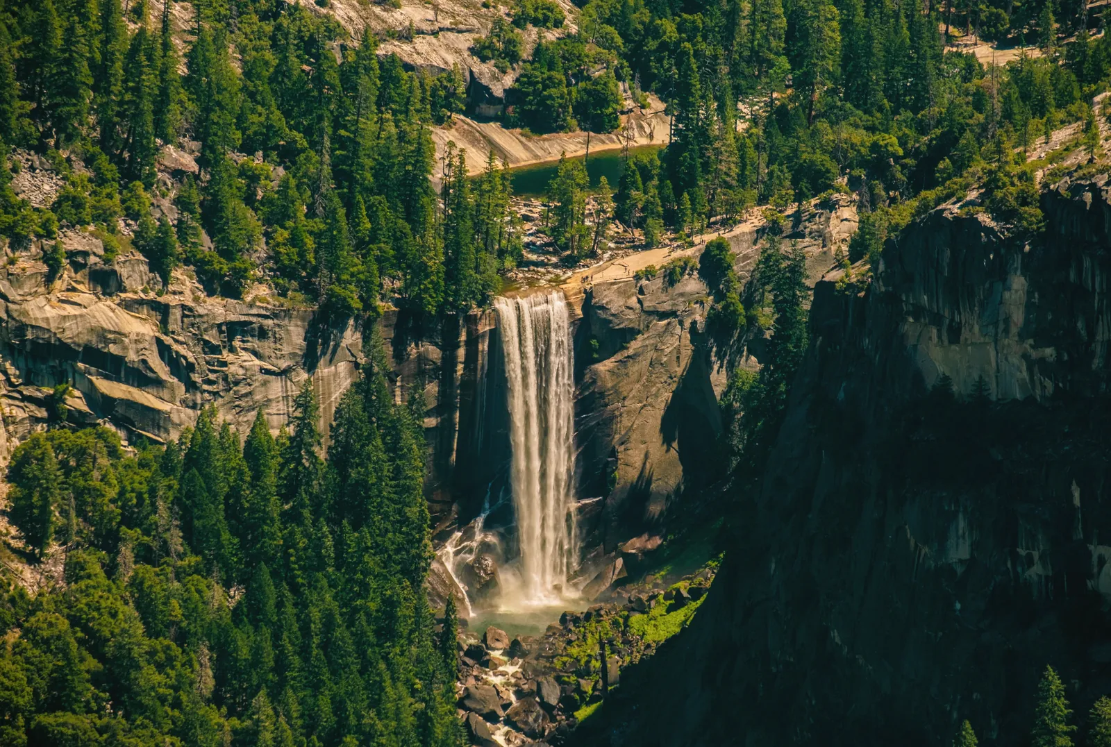 Breathtaking view of a cascading waterfall in Yosemite Valley, surrounded by lush greenery.